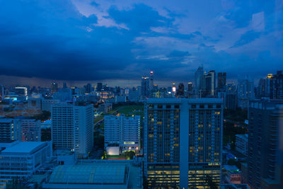 Illuminated buildings in city against blue sky