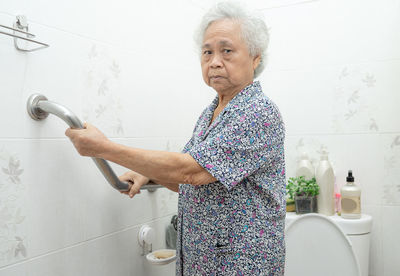 Mid adult woman standing against wall at home