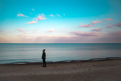 Full length of man standing on beach against sky during sunset