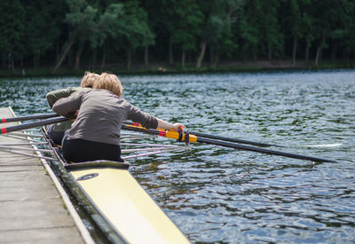 Rear view of man sitting on boat in river