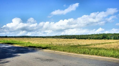 Road amidst field against sky
