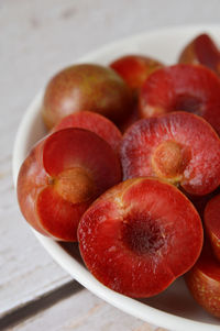 Close up half cut of delicious vietnamese red plums with pits on plate.