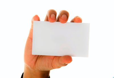 Close-up of hand holding paper against white background