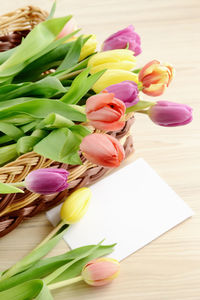 Close-up of tulips in basket with greeting card on table