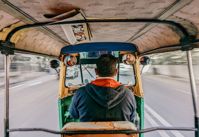 Rear view of man riding autorickshaw 