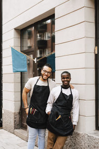 Portrait of male barbers standing outside hair salon