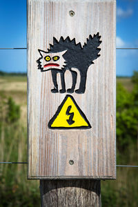 Close-up of sign on wooden post