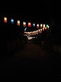 Illuminated street amidst buildings in city at night