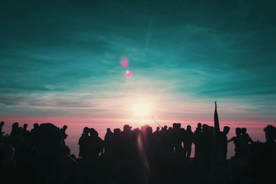 Silhouette people at music concert against sky during sunset