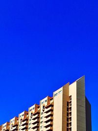 Low angle view of apartment building against clear blue sky