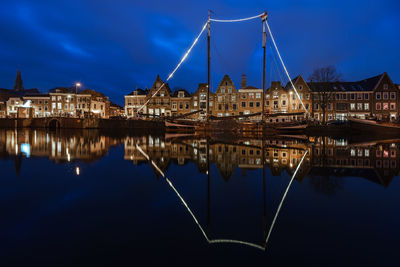 Reflection of boats and buildings in canal against sky at dusk