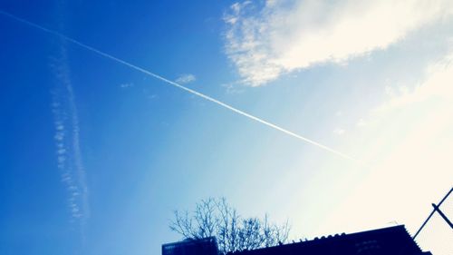 Low angle view of vapor trails against blue sky