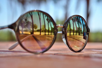 Close-up of sunglasses with trees reflecting on table