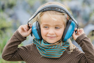 Close-up of smiling girl listening music over headphones