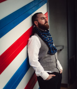 Thoughtful mid adult bearded man leaning on colorful wall