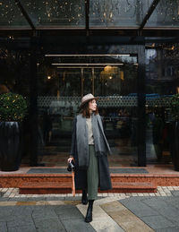 Full length of woman standing against graffiti wall