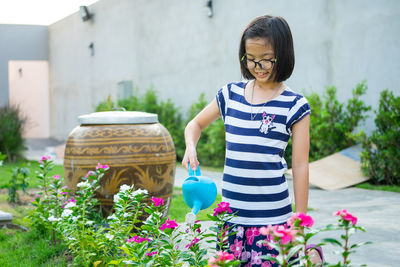 Closeup asian little girl watering the colorful blossom flowers by watering can