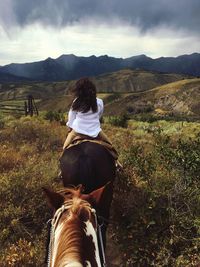 Woman sitting on horse with mountain in background