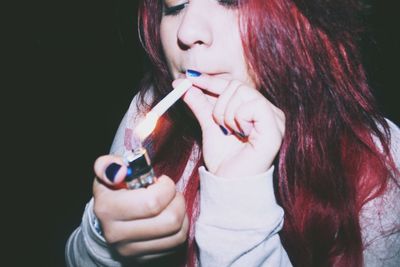 Close-up of young woman lighting cigarette