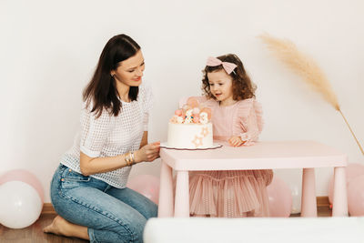 A young mother and her little daughter celebrate their birthday with a cake.