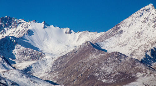 Aerial view of snowcapped mountains against clear blue sky