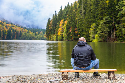 Rear view of man standing by lake