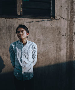 Portrait of young man standing against wall