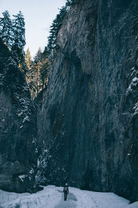 Rear vie of woman against rock formation on snow