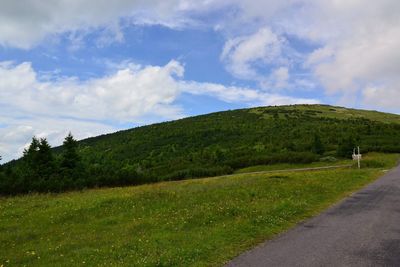 Scenic view of road amidst field against sky