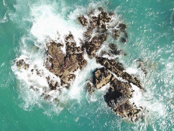 High angle view of waves splashing on rocks in sea