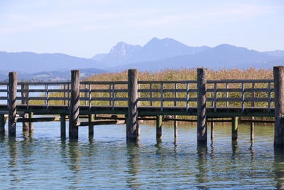 Wooden posts in lake against sky