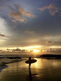 Silhouette man on beach against sky during sunset