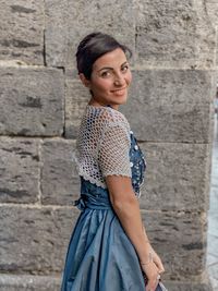 Portrait of young woman standing against wall