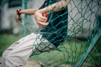 Midsection of boy sitting on fence