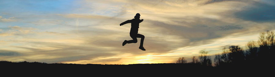 Silhouette man jumping against sky during sunset