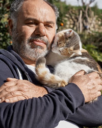 Bearded mature man happy holding and hugging his cute cat. friendship, love, love of animals. 