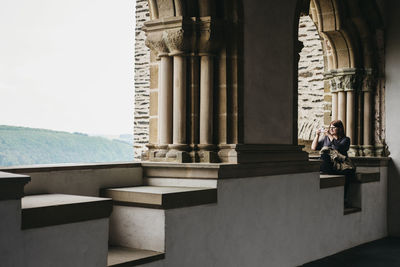 Side view of man sitting on building