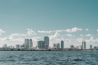 Sea by buildings against sky in city