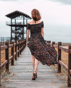 Rear view of woman walking on pier against sea