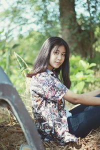 Side view portrait of young woman sitting on field