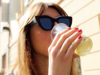 Low angle view of woman drinking soda on sunny day