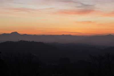 Scenic view of silhouette mountains against orange sky
