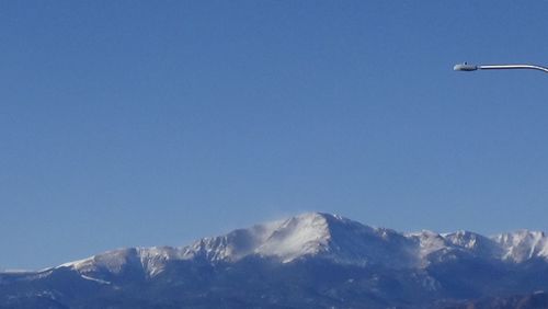 Low angle view of snowcapped mountain against clear blue sky