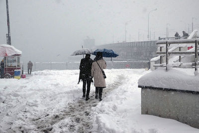 People working on snow covered shore during winter