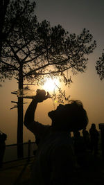 Silhouette man using smart phone against sky during sunset