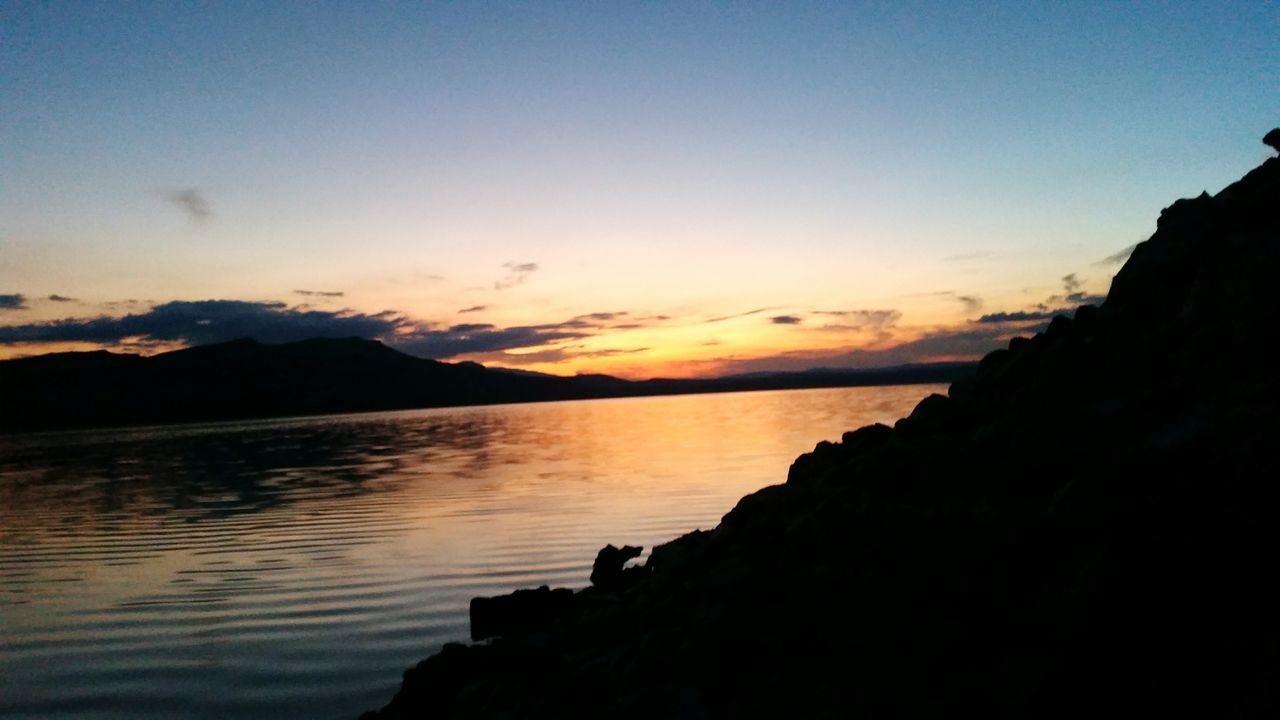 tranquil scene, water, scenics, tranquility, sunset, beauty in nature, silhouette, sea, sky, idyllic, nature, mountain, reflection, calm, lake, dusk, copy space, outdoors, non-urban scene, waterfront