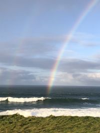 Scenic view of rainbow over sea against sky