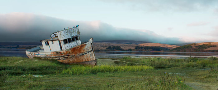 Abandoned boat on shore against sky