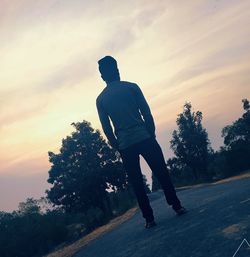 Rear view of silhouette man walking on road against sky