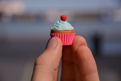 Cropped hand of woman holding small muffin